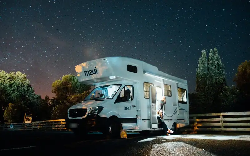 Witte camper 's nachts onder een sterrenhemel, met licht uit de open deur