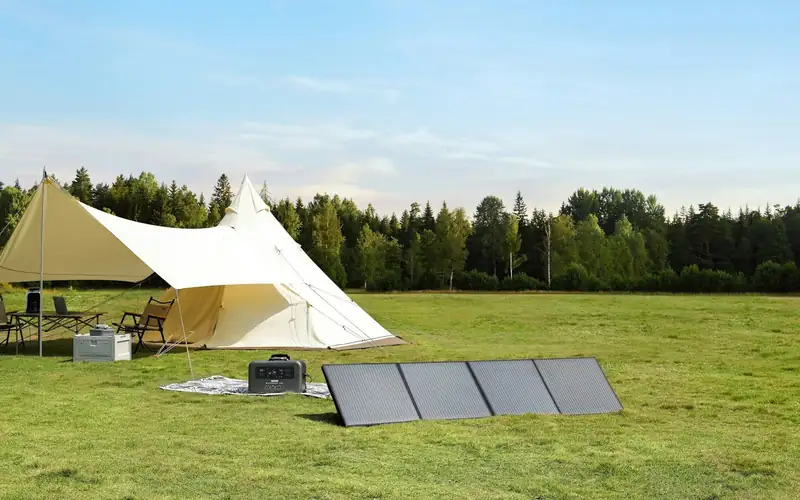 Witte tipitent op een grasveld met drie zonnepanelen plat in het gras